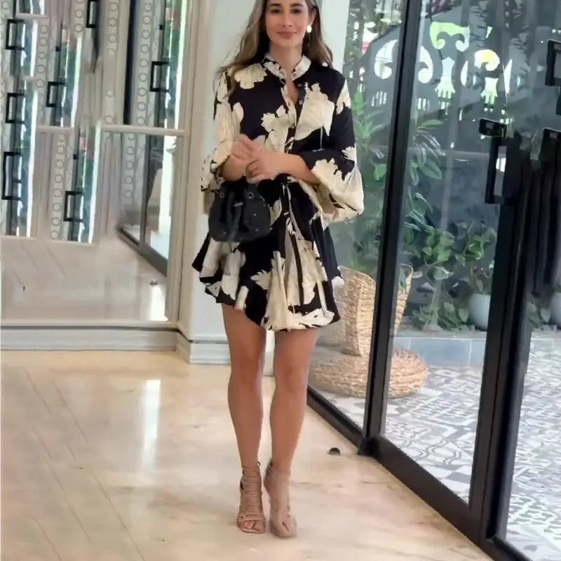 Woman wearing a black and white floral print dress with long sleeves and high heels.