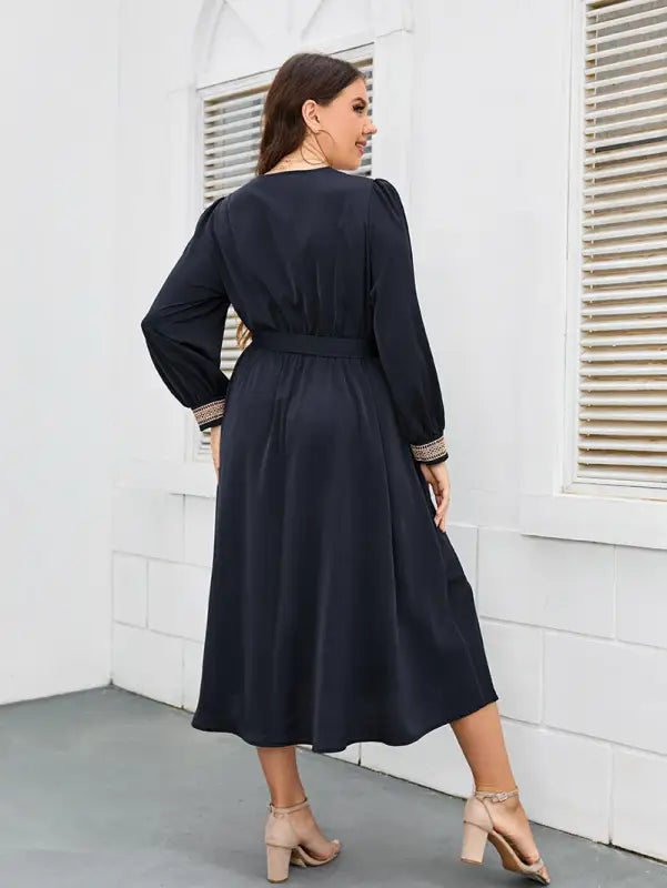 Navy blue long-sleeved midi dress with embellished cuffs and a cinched waist.