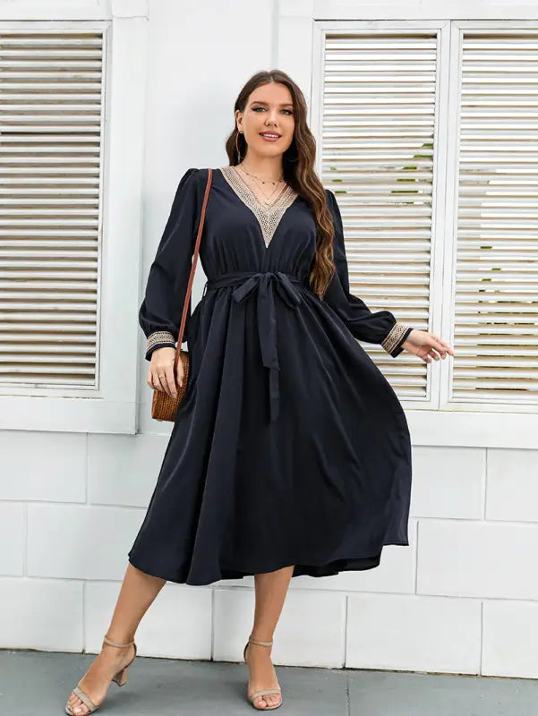 Navy blue midi dress with long sleeves and a v-neckline adorned with gold trim.