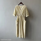 Cream-colored Retro V Neck Pleated Midi Dress with pockets on a wooden hanger