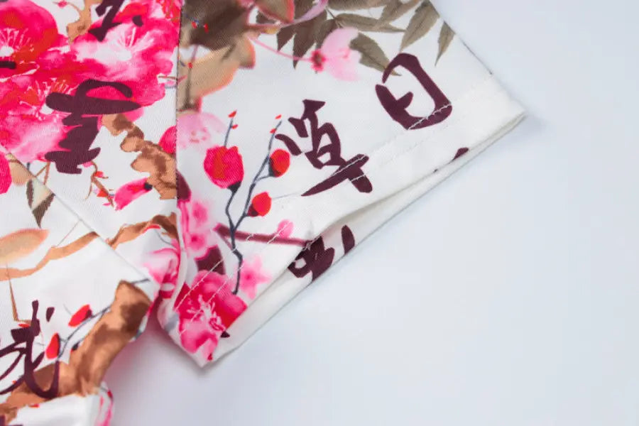 Floral-patterned fabric with pink blossoms and Japanese calligraphy.