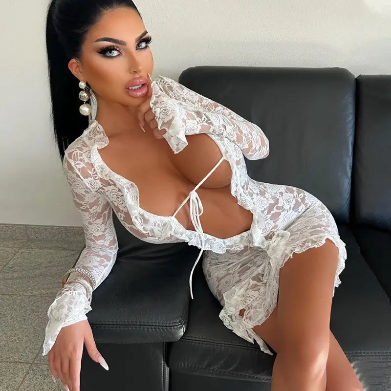 Woman wearing a revealing white lace outfit posing on a leather couch.