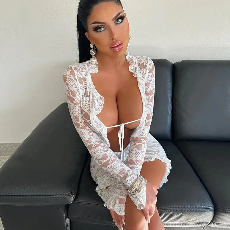 Woman wearing a revealing white lace top sitting on a leather couch.