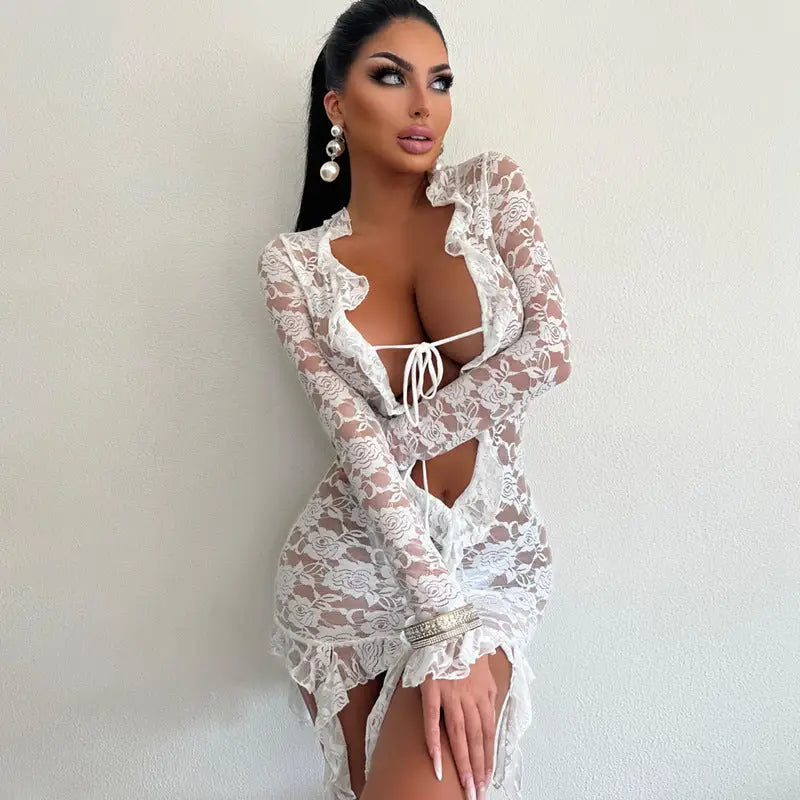 Woman wearing a revealing white lace dress with long sleeves and a plunging neckline.