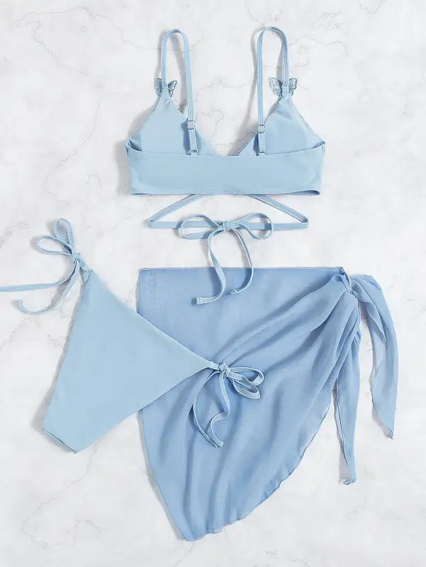 Light blue three-piece bikini set with a wrap skirt.