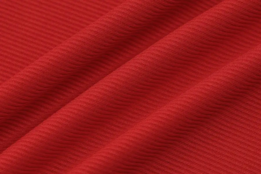 Red textured fabric with diagonal folds or pleats.