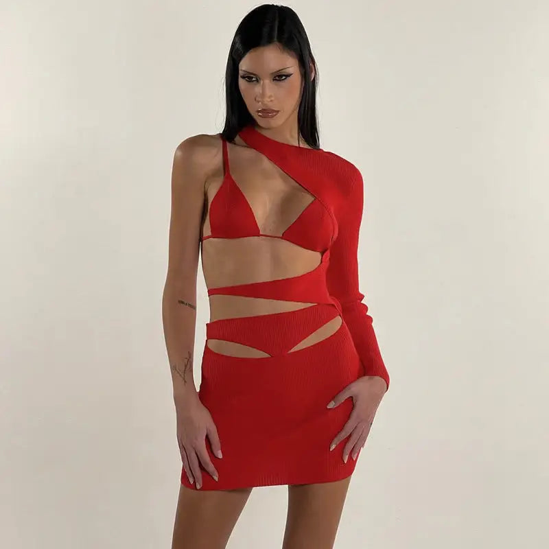 Revealing red dress with asymmetrical cutouts and one long sleeve.