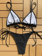 Bikini with a white triangle top and black crochet-style bottom.