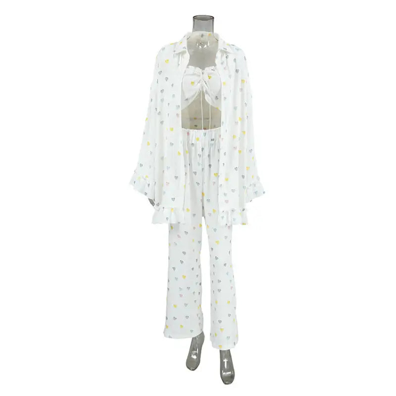 White pajama set with a floral pattern consisting of a top, pants, and robe displayed on a mannequin.