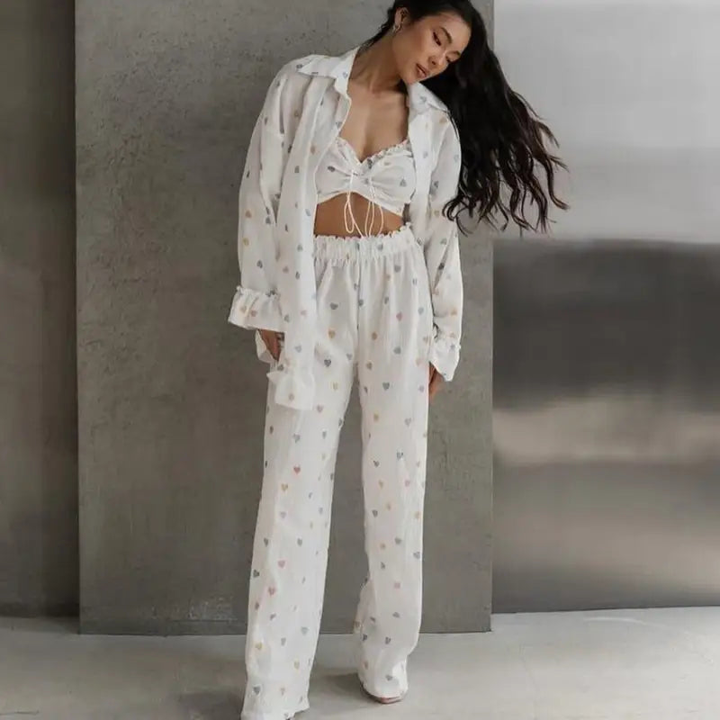 Woman wearing a white heart-patterned pajama set with a crop top and loose pants.