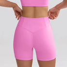 Bright pink high-waisted workout shorts on a fit torso.