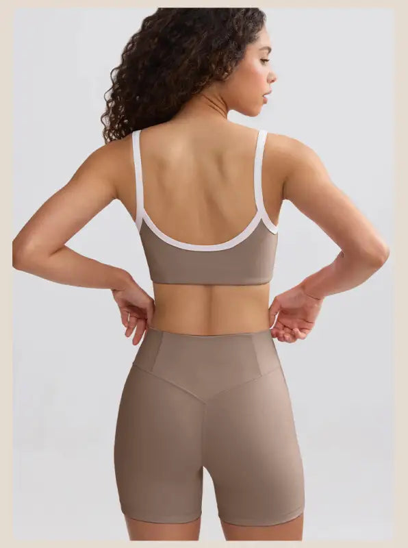 Woman wearing a taupe sports bra and matching high-waisted shorts, viewed from behind.