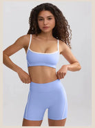 Young woman with curly hair wearing a light blue sports bra and matching shorts.