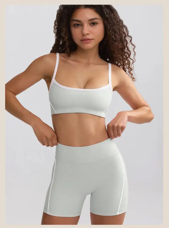 Young woman with curly hair wearing a white sports bra and matching high-waisted shorts.