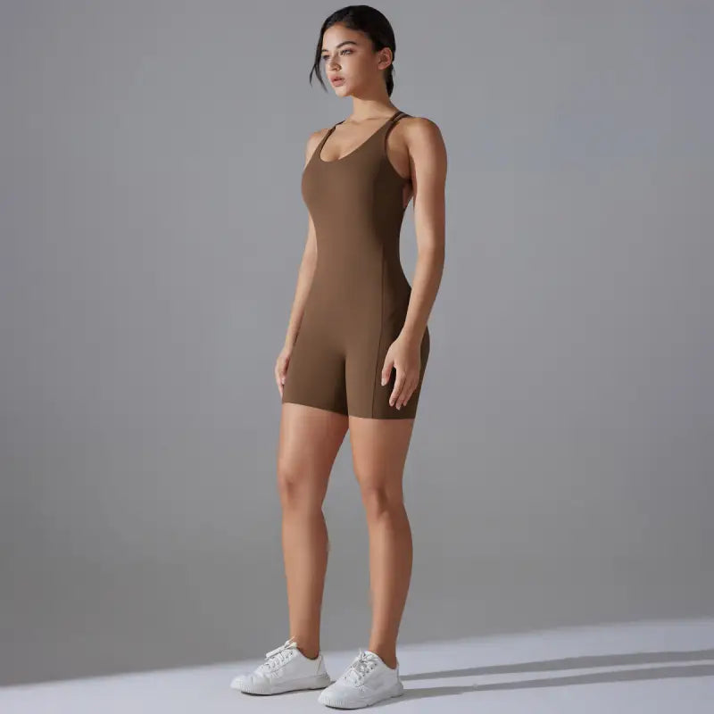 Brown form-fitting sleeveless bodysuit worn by a woman with white sneakers.