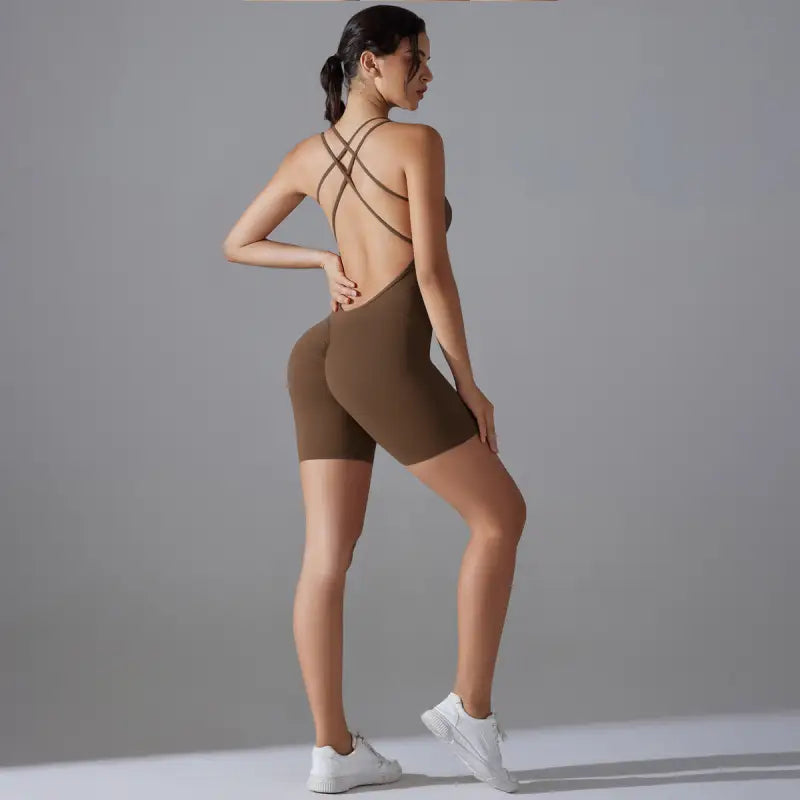 Brown form-fitting bodysuit with crisscross back straps and shorts-length legs.