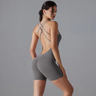 Gray form-fitting workout bodysuit with a strappy open back design.