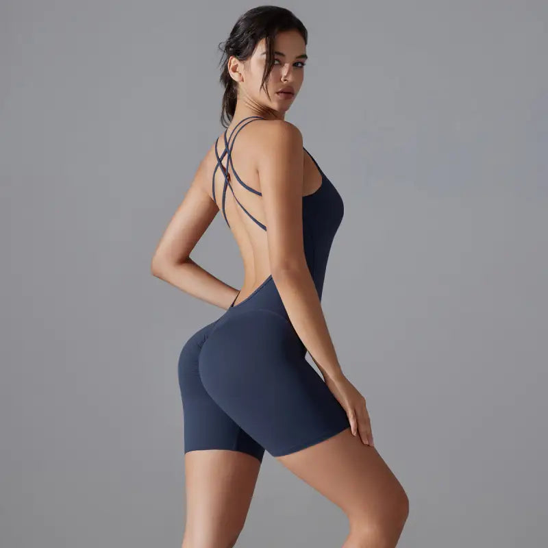 Woman wearing a navy blue workout bodysuit with crisscross back straps.